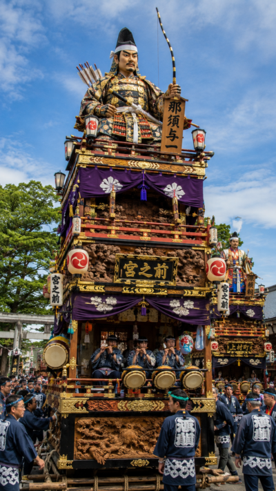 神奈川県藤沢市の鵠沼皇大神宮例大祭で歴史上の人物や物語の主人公をかたどった巨大な人形を最上部に載せた高さ約8メートルの豪華な人形山車が祭囃子とともに境内へ集まる光景
