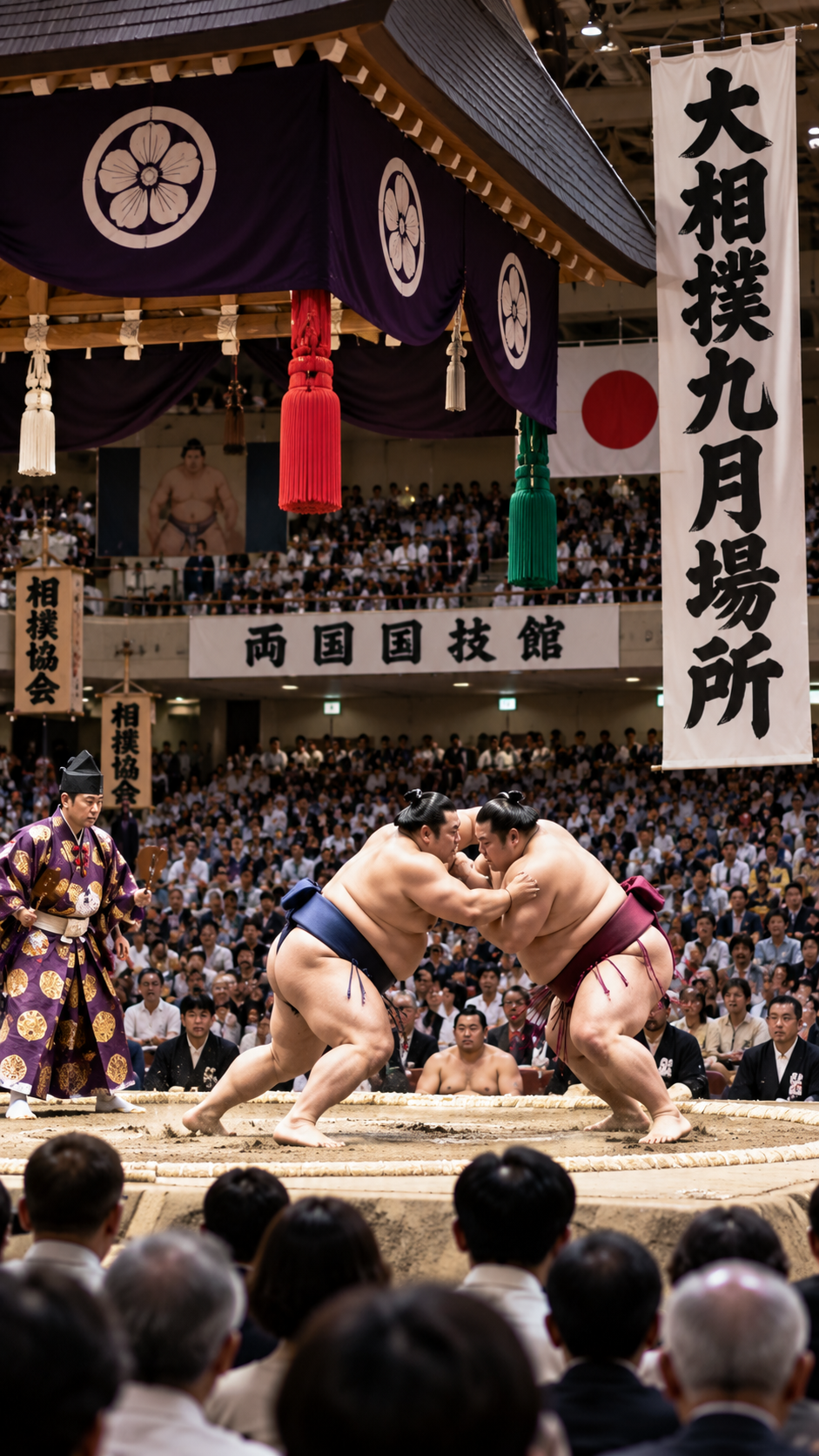 東京都墨田区の両国国技館で大相撲九月場所が開催され、力士が土俵上で激しくぶつかり合い、多くの観客が見守る伝統的な大相撲の風景