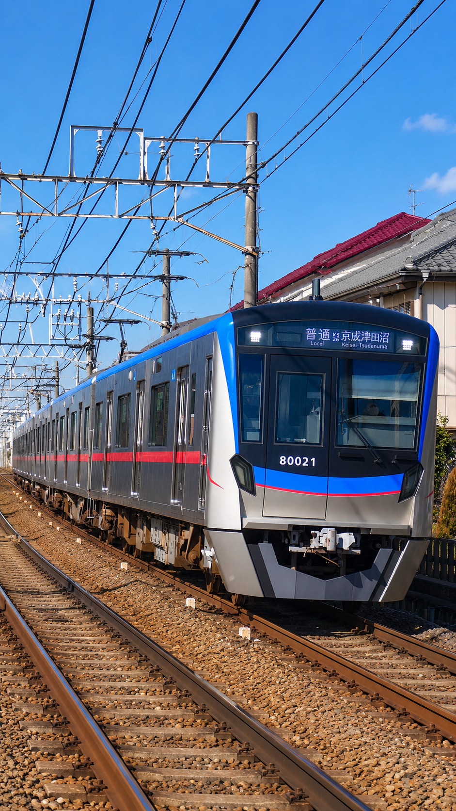 千葉県を走る京成松戸線の電車が駅を出発し、住宅地の中を走り抜ける鉄道風景