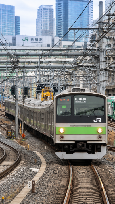 東京都心の高層ビルや住宅街を走る黄緑色のラインが特徴的な山手線の電車と東京の街並み