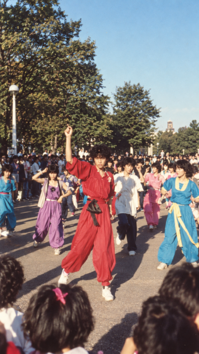 原宿の歩行者天国で個性的な衣装をまとい、音楽に合わせて踊るたけのこ族の若者たちを再現した昭和のストリート文化のイメージ