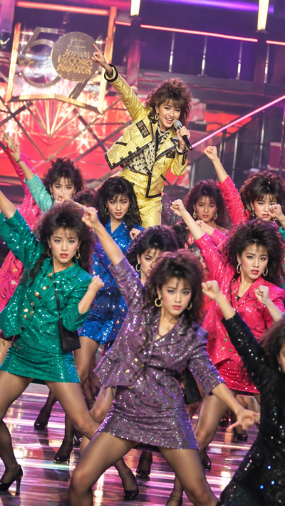 派手なバブル期風衣装と扇子を使って踊るバブリーダンスの女性たち