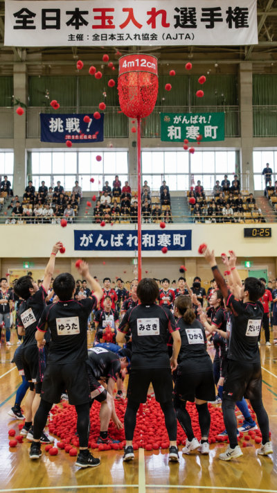北海道和寒町総合体育館で全日本玉入れ選手権が開催され、選手たちが高さ4m12cmのバスケットを目指して一斉に玉を投げる競技の風景