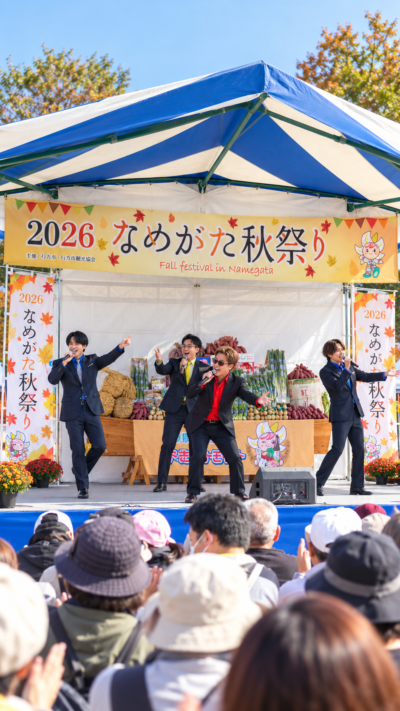茨城県行方市の霞ケ浦ふれあいランドで開催されるなめがた秋祭り2026で、飲食や雑貨のブース、ステージイベントを多くの来場者が楽しむ会場風景